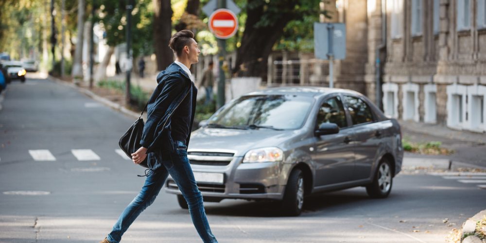 Young man cross the street at a crosswalk